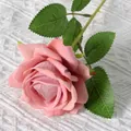 Single artificial pink velvet rose with realistic green leaves on white knit background - Elsa Bean Paste