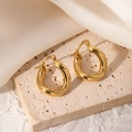 Détail macro de boucles d'oreilles créoles torsadées dorées sur pierre beige - Créole Épaisse Irrégulière (JJE0023)