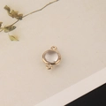 Macro detail of a round crystal pendant with gold plated copper frame and dual loops - 1 Piece / Transparent