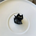 Detail shot of a black cat hair claw clip made of acetate with silver glitter and yellow eyes - Mini Magic Black Cat