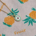 Goldene Halskette mit minzgrünem Emaille-Auge Anhänger auf Ananas-Muster Stoff - Minzgrün