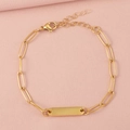 Close-up of a gold paperclip chain bracelet with a polished engravable bar on pink fabric - 1 Bar / Gold