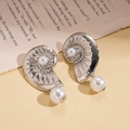 Detailed close-up of seashell-shaped metal earrings with white hanging pearls on book - Silver (Silver Pin)