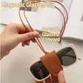 Brown leather magnetic clip for glasses with lanyard shown holding off-white sunglasses - Lanyard Style / Brown