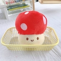 Close-up of a red plush mushroom keychain with a smiling face in a yellow basket - Red