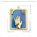 Détail d'un pendentif carré émaillé avec motifs étoile, lune et soleil sur fond blanc - Main de Hamsa-Bleu
