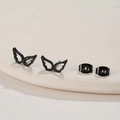 Macro shot of matte black hollow angel wing stud earrings on a minimalist white stand - 672 Black (Butterfly Wings)