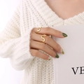 Anelli dorati minimalisti a forma di U indossati da una modella che tiene un libro - Taglia US 7 (Regolabile) / Oro