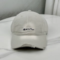 Close-up of beige distressed cotton baseball cap with blue embroidered logo and frayed brim - Gray