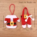 Porte-couverts mini costume de Père Noël avec étiquette de poids sur fond bois brun - Ensemble Haut et Pantalon à Boutons en Plastique
