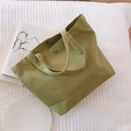 Dettaglio della borsa tote in tela verde erba con bottone a pressione in ottone e manici spessi - Verde Fagiolo