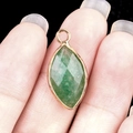 Marquise cut forest green gemstone pendant with gold metal edging held in hand - Green Strawberry Quartz