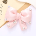 Detail view of pink satin bow accessory with sparkling rhinestones on light background - Light Pink