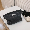 Detail der schwarzen Make-up-Tasche mit Herzprägung und einfachem Wunsch-Etikett - Schwarz