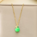 Détail d'un pendentif pomme verte sur une chaîne dorée sur fond de tissu beige - Pomme Verte (KN292108-Z)
