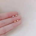 Minimalist 925 silver and gold bear stud earrings held on a fingertip for scale - Bear / Silver