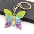 Macro shot of gradient colorful butterfly keychain with shimmering glitter and gold chain - Green