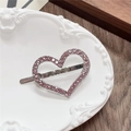 Dettaglio di un fermaglio a cuore argento con strass rosa su un piatto vintage - Cuore-LOVE Rosa