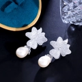 Dettaglio macro di orecchini a fiore con zirconi e perle a goccia su vassoio elegante - Oro Bianco