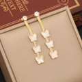 Detail of gold butterfly drop earrings with white charms on a vintage book background - 3# Earrings
