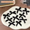 Set of 10 black satin DIY mini bows for crafts, approx 4cm diameter on a white plate - Wide Black