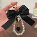 Elegant black satin bow keychain featuring pearl beads and golden metal hardware - Black