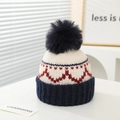 Dettaglio ravvicinato di un berretto invernale in maglia con pompon colorato e cuori - 2-7 Anni / Blu navy