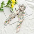 Detail of floral chiffon hair scrunchie with long ribbons on a decorative magazine - Pink