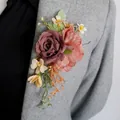 Caramel wedding boutonniere featuring purple roses and orange silk flowers on a coat - Caramel color