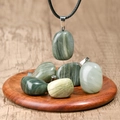 Irregular green natural stone pendant necklace with black cord on wooden display - Labradorite