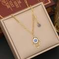 Hamsa-Hand-Halskette mit blauem Evil-Eye-Anhänger in einer beigen Schmuckschatulle - Hamsa Hand Böser Blick Halskette