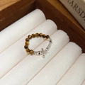 Primer plano detallado de un anillo de cuentas de ojo de tigre con colgantes de plata - Anillo De Cuerda Elástica Simple Y Elegante Con Cuentas De Ojo De Tigre De Plata N.° 29