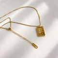 Macro shot of 18K gold sun square pendant necklace with lobster clasp on white surface - Square Sun Cloud Style