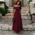 Elegante abito lungo bordeaux con spalle scoperte da donna su sfondo in pietra - S / Borgogna