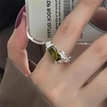 Close-up of olive green gemstone ring with white stones on a silver-tone band - Silver Emerald Green Stone Inlaid