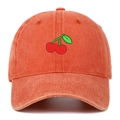 Close-up of cherry embroidery and vintage washed texture on orange cotton baseball cap - Orange