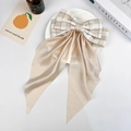 Dettaglio di un fermaglio per capelli con fiocco a quadri beige e nastri lunghi su sfondo - Champagne