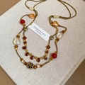 Détail d'un collier multicouche vintage avec gouttes d'ambre et accents de fleurs en céramique - Or-Rouge-Café