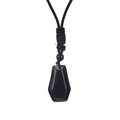 Dettaglio della collana con pendente geometrico nero e cordino intrecciato su sfondo bianco - Ossidiana