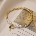 Detalle de pulsera de perlas con dije de pájaro dorado y gema azul en forma de gota - Pájaro de Gota de Agua Azul