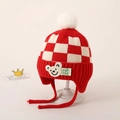 Detail van rood-wit geruite gebreide babymuts met beerpatch en witte pluche pompon - Rood Schaakbord Beer Stijl / Rood