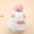 Macro detail of infant knit beanie featuring pink floral patterns and plush pom-pom - 0-12 Months / White