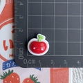 Macro shot of a mini red resin cherry charm with a smiley face on a centimeter scale pad - Large Cherry with Smiley Face