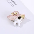 Creative tooth shaped brooch with pink striped hat and sunglasses on a stylish background - Pink
