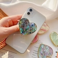 Dettaglio supporto per telefono a cuore con trama in conchiglia e bordo dorato - Impugnatura Cuore Oro / Conchiglia di Abalone Blu