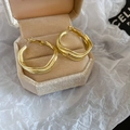 Detailed view of large irregular wavy gold hoop earrings in an octagonal jewelry box - Gold