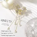 Detailed view of butterfly hair claw with white rhinestones and pearl tassels on white fabric - Full Diamond 4 Pearl Tassel Butterfly