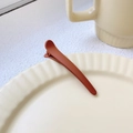 Single reddish brown matte duckbill hair clip on a beige ceramic plate with 8cm length - Orange