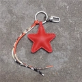 Détail macro du porte-clés étoile en cuir rouge avec ruban sur fond en béton brut - Rouge
