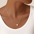 Gros plan d'un collier pendentif cœur doré minimaliste porté au cou d'une femme - Or Collier Cœur Unique